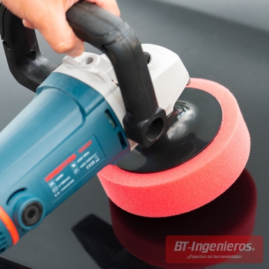 Pulidora eléctrica utilizando esponja de corte roja sobre superficie negra