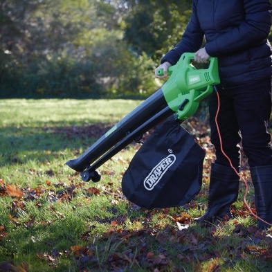 Soplador aspirador de hojas Draper 3000W en uso sobre césped con bolsa de recogida y cable eléctrico
