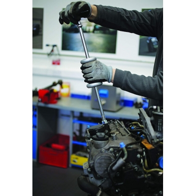 Martillo de inercia deslizante siendo utilizado por un mecánico para extraer un componente de motor diésel en taller.