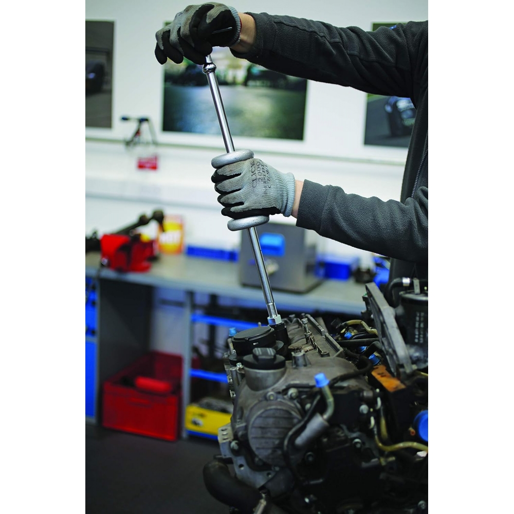 Martillo de inercia deslizante siendo utilizado por un mecánico para extraer un componente de motor diésel en taller.