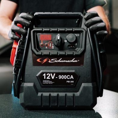 Vista frontal del arrancador Schumacher PBI200 profesional con pinzas pesadas y pantalla LED.