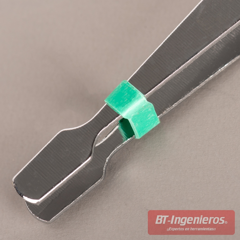 Detalle de pinza de precisión con punta plana y clip verde de sujeción sobre superficie gris