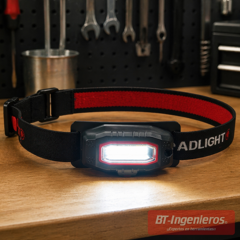 Linterna frontal LED COB encendida sobre mesa de taller